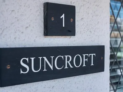 a sign on the side of a building that reads sunset at Suncroft in Port Isaac