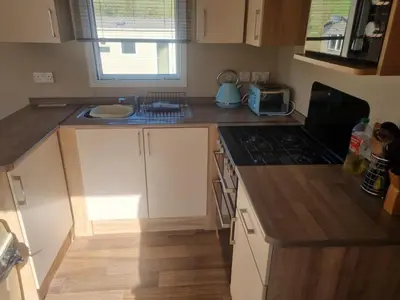 a kitchen with white cabinets and a stove top oven at Newquay Bay Porth Caravan - 6 berth in Newquay