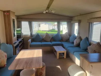 a living room with a blue couch and a table at Newquay Bay Porth Caravan - 6 berth in Newquay