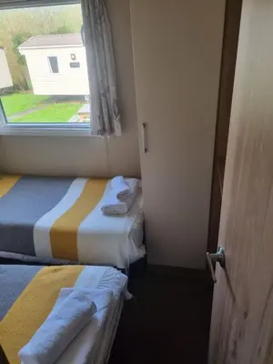 a small room with two beds and a window at Newquay Bay Porth Caravan - 6 berth in Newquay