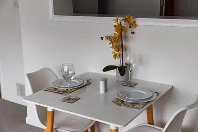 a white table with two plates and glasses on it at 1 Chatsworth Riverscape Apartments - Riverview apartment in great location with free parking overlooking the Gannel just a short walk from Newquays incredible beaches and local amenities in Newquay
