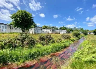 a dirt road in a field with houses in the background at Tranquil Retreat at River Valley Country Park in Penzance