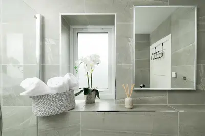 a bathroom with a mirror and a sink with towels at Sandy Cove in Penzance