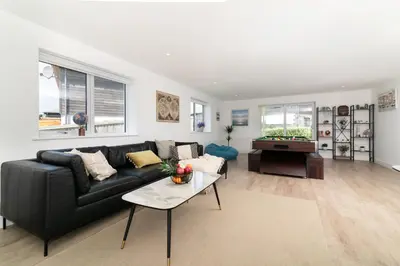 a living room with a black couch and a table at Sandy Cove in Penzance