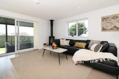 a living room with a black couch and a table at Sandy Cove in Penzance