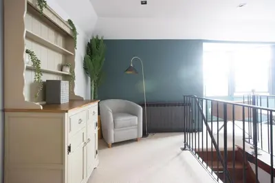 a living room with a chair and a staircase at 4 Bedroom Cottage with panoramic Harbour views in Falmouth