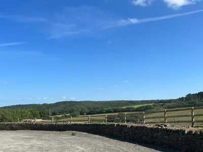 a stone wall with a fence and a field at Number Four - The Old Stable Block in Wadebridge