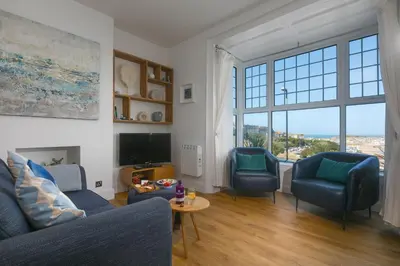 a living room with a blue couch and two chairs at Sea Bre in St Ives