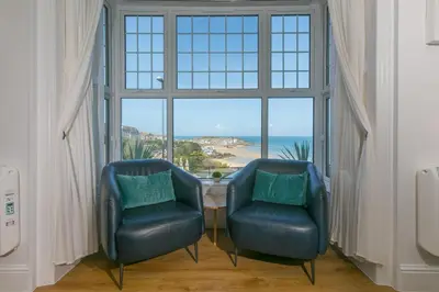 two blue chairs in a room with a large window at Sea Bre in St Ives