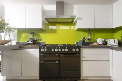 a kitchen with white cabinets and a black stove at Treheyl, Pentire, Newquay in Newquay
