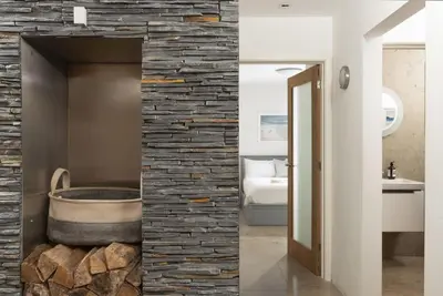 a bathroom with a stone wall and a tub at Treheyl, Pentire, Newquay in Newquay