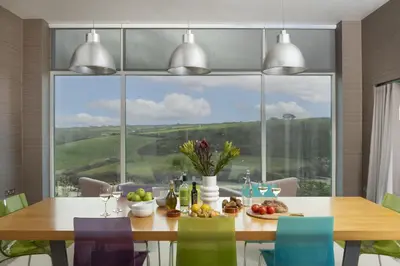 a dining room with a table and a large window at Treheyl, Pentire, Newquay in Newquay