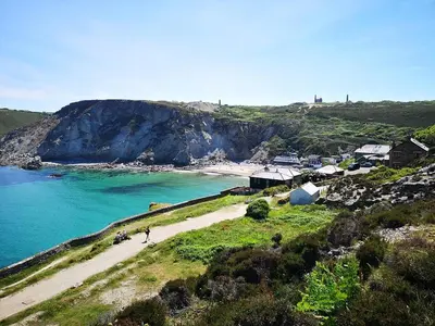 a group of people walking on a beach next to the ocean at Howlyek, in St Agnes Village in St. Agnes