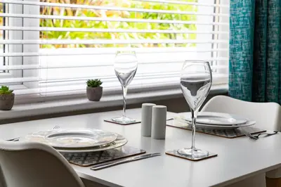 a white table with two wine glasses on it at 2 Chatsworth Riverscape Apartments - Peaceful apartment in great location with free parking overlooking the Gannel just a short walk from Newquays incredible beaches and local amenities in Newquay