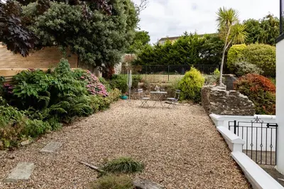 a garden with a table and chairs in a yard at 2 Chatsworth Riverscape Apartments - Peaceful apartment in great location with free parking overlooking the Gannel just a short walk from Newquays incredible beaches and local amenities in Newquay
