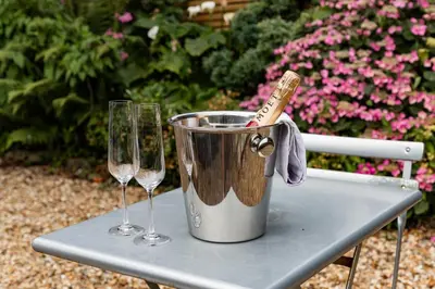 a bucket and two wine glasses on a table at 2 Chatsworth Riverscape Apartments - Peaceful apartment in great location with free parking overlooking the Gannel just a short walk from Newquays incredible beaches and local amenities in Newquay