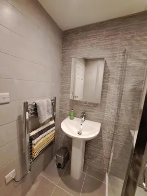 a bathroom with a white sink and a shower at 2 Chatsworth Riverscape Apartments - Peaceful apartment in great location with free parking overlooking the Gannel just a short walk from Newquays incredible beaches and local amenities in Newquay
