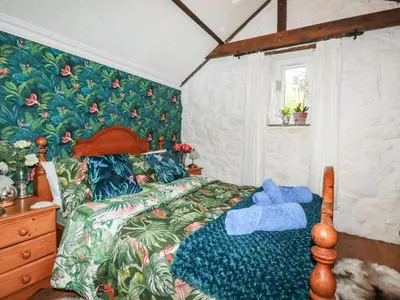 a bedroom with a bed with a tropical wallpaper at Carminow Barn in Bodmin