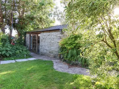 a stone house with a garden in a yard at Carminow Barn in Bodmin