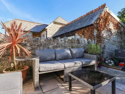 a patio with a couch and a fence at Carminow Barn in Bodmin