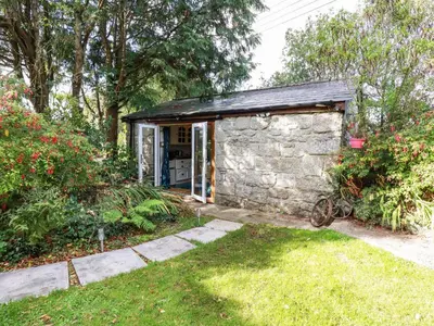 a stone house with a garage in a yard at Carminow Barn in Bodmin