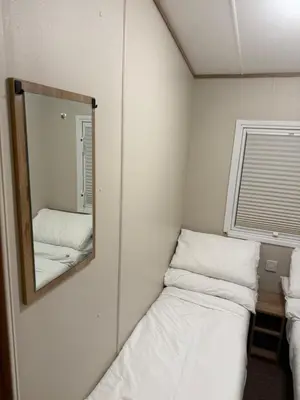 a small room with a mirror and two beds at Oakley Newquay Bay Resorts in Porth