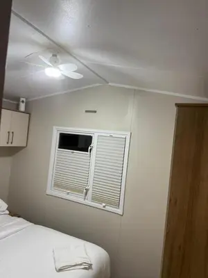 a bedroom with a ceiling fan and a window at Oakley Newquay Bay Resorts in Porth