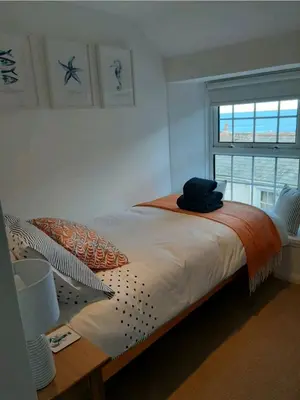 a bedroom with a large bed with a window at Cosycot in Gorran Haven