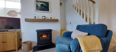 a living room with a blue chair and a fireplace at Cosycot in Gorran Haven