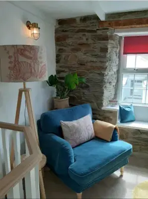a blue chair in a living room with a window at Cosycot in Gorran Haven