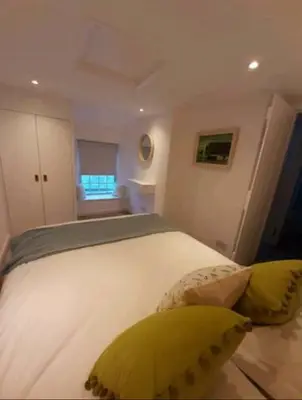 a bedroom with a large white bed with yellow pillows at Cosycot in Gorran Haven