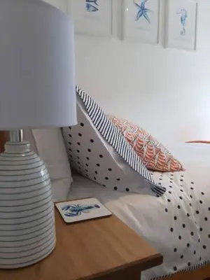 a lamp on a table next to a bed at Cosycot in Gorran Haven