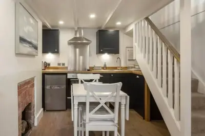 a kitchen with a table and chairs and a staircase at Cosycot in Gorran Haven