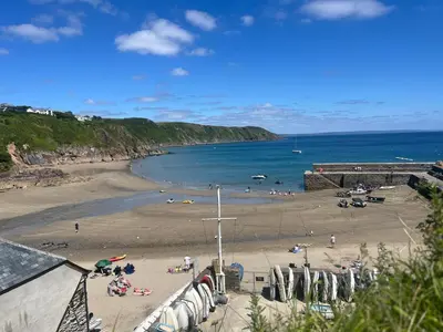 a beach with people on the sand and the ocean at Cosycot in Gorran Haven