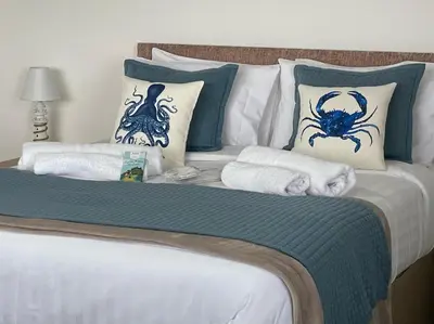 a bed with blue and white sheets and pillows at Sea Spirit - Sweeping Sea Views first floor spacious modern apartment in Looe- with FREE parking! in Looe