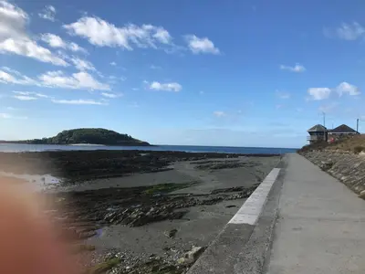 a road leading to the ocean with a house in the distance at Sea Spirit - Sweeping Sea Views first floor spacious modern apartment in Looe- with FREE parking! in Looe