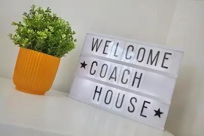 a sign that says welcome coach house next to a plant at 2022 Stylish Flat in Central Hayle in Hayle