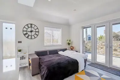 a bedroom with a bed and a clock on the wall at 2022 Stylish Flat in Central Hayle in Hayle
