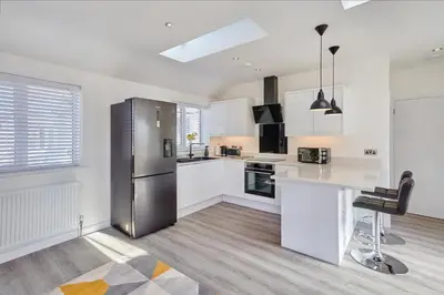 a kitchen with white cabinets and a stainless steel refrigerator at 2022 Stylish Flat in Central Hayle in Hayle