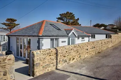a white house with a stone wall at 2022 Stylish Flat in Central Hayle in Hayle