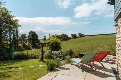 a patio with two chairs and a view of a field at Daydreamer Cottage in Padstow
