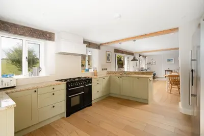 a large kitchen with white cabinets and black appliances at Daydreamer Cottage in Padstow