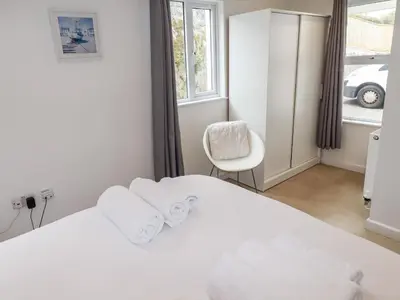 a bedroom with a bed and a chair and a window at Ocean Gate in Carbis Bay