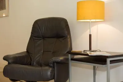a black leather chair next to a table with a lamp at The Point in St Ives