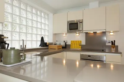 a kitchen with white cabinets and a large window at The Point in St Ives