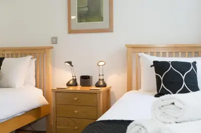 a bedroom with two beds and a nightstand with two lamps at The Point in St Ives