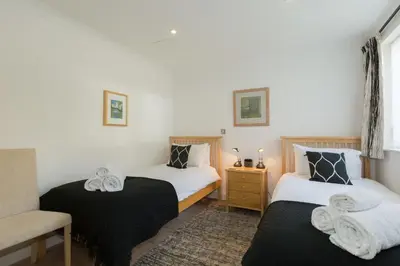 two beds in a room with a chair and a couch at The Point in St Ives