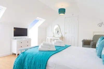 a white bedroom with a bed with towels on it at Atlantic Blue in Carbis Bay