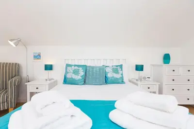 a bedroom with a white bed with blue pillows at Atlantic Blue in Carbis Bay