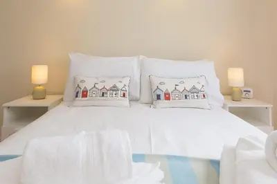 a white bed with pillows on it with two lamps at Atlantic Blue in Carbis Bay